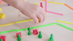 Child and adult hands engaged in educational game using colorful plastic counters and counting sticks on wooden table, Early childhood development, promotes fine motor skills