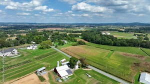 Pennsylvania farmland during bright summer day. Aerial rising reveal shot.