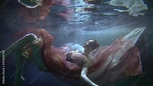 A beautiful woman elegantly floating underwater in a dress like a mermaid in a fairy tale