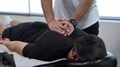 Therapist giving upper back massage to male athlete after workout....