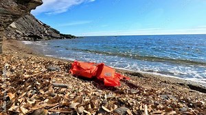 orange life jacket abandoned in the sand next to the beach shore