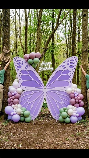 Magical butterfly garden party setup! 🦋 This custom setup features oversized lavender butterfly wing backdrops, custom-built cylindrical pedestals, and a neon