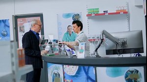 Pharmacy technician at drugstore counter scanning pharmaceutical products from elderly customer shopping basket. Older man buying sickness preventive medicaments in apothecary