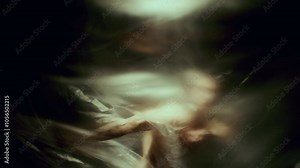 Shirtless dancer performing mesmerizing movements behind translucent plastic sheet, creating sense of entrapment and struggle with dramatic highlights and shadows