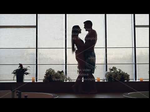 Silhouette of loving young people in bathing suits meeting in modern day spa, hugging and kissing