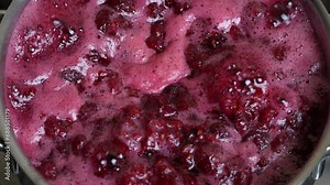 Preparation of freshly picked red raspberries with sugar to make raspberry jam, close up. Cooking homemade raspberry fruit jam in a saucepan. Boiling raspberry fruits for jam