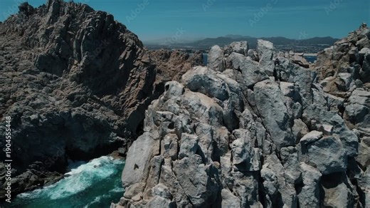 Drone flys over rugged rock revealing iconic Land's End Arch in Cabo San Lucas