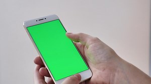Download POV scrolling smartphone with green screen on white isolated background close-up in female hands. Modern technology, phone in real life for free