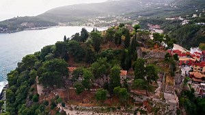Aerial drone shot over the castle of Parga in the Epirus region in Greece. Camera moving forward unveil the stunning beach underneath the hill.