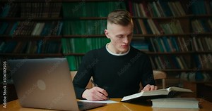 The guy is reading a book and makes notes in the librery. Education in the library. 4K