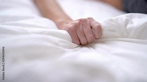 Woman's hand squeezing white sheet in erotic excitement