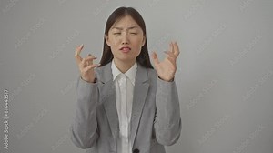 Frustration overload, mad expression of young chinese woman, wearing jacket, standing with arms raised, crazy shouting and yelling isolated over a white background