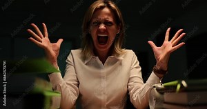 Angry female manager screams loud in office raising hands. Emotional woman in white shirt sits at table while lightning flashing out of window at night