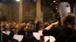 Upright bass at classical concert with musicians and conductor in the background. Soft focus. Stock Video