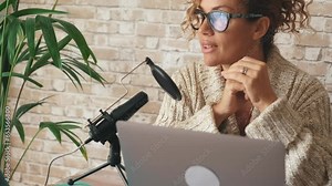Young adult woman working at home with laptop and microphone. Customer care and businesswoman job activity. Female people using computer at home office sitting at the desk. Online modern business
