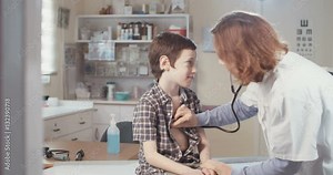 Female doctor using a Stethoscope to check a young boy