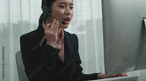Asian customer support operator wearing headset and microphone working at her desk with laptop. Enthusiastic female employee provide customer service, supportive call center agent helping customers. Stock Video