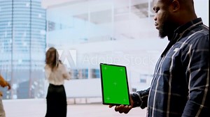 Real estate agents and client examine blueprints next to a green screen, working together on new modern office space development layout. Sharing workspace design vision. Camera A.