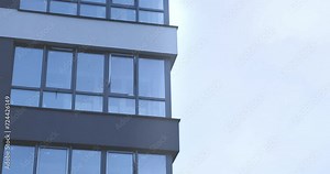 Modern floor-to-ceiling windows in multi-story building, close up. Facade of fashionable luxury business house. Metal-plastic glass window architecture in morning sunlight. Urban skyscraper view