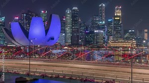Aerial view over Helix Bridge and Bayfront Avenue with traffic day to night transition timelapse at Marina Bay from above with illuminated skyscrapers skyline on a background, Singapore
