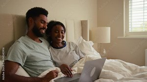 Couple at home in bed looking at laptop computer together - shot in slow motion