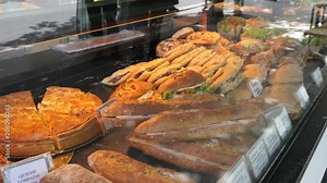 Baguette sandwiches layout behind glass chowcase at food point on a street of Paris city center