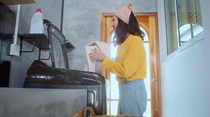 Download young woman washing with washing machine in her House for free