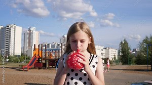 a little girl inflates a red balloon in a city children's park in summer 4k slow motion