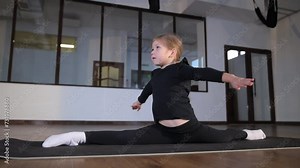 The acrobat girl does splits in the gym.