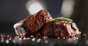 Grains of salt and other spices falling onto plate with beautiful beef steak. Mignon fillet being prepared for serving - art food, gourmet meal 4k footage close up