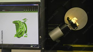 medical laboratory, modern dantist apparatus scans artificial jaw in lighting and shows on computer monitor