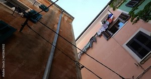 Traditional houses of an old Mediterranean town with windows with shutters, ivy-covered walls and linen to dry outdoors. View from bottom to top.