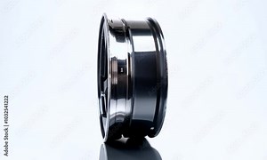 Chrome Wheel: Side View of a shiny, chrome car wheel, with black spokes and a reflective surface. The wheel is isolated on a white background and tilted slightly.