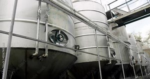 Alcohol production concept. Large steel barrels for wine fermentation. Wine production plant. Steel wine distilling tanks. Modern winemaking facility or winery.