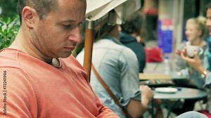 Man reading newspaper in the street cafe, steadycam shot