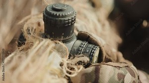 A gloved hand delicately adjusts the optic sight of a sniper rifle, a crucial element in the precise execution of a sniper's duty, with each meticulous movement captured in fine detail. Camera 8K RAW