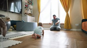 Baby's first steps. Father helps encourages Toddler to take bold first steps at home. Parent lends helping hand for teaches of baby. Toddler walk at home. Baby first active steps on father's day