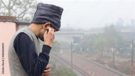 A man wears an earpod during a cold winter morning in Delhi, showing modern communication, technology use, and everyday urban lifestyle in winter conditions.