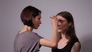 Professional makeup artist putting cosmetics on model face