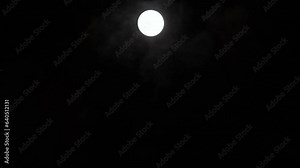 Timelapse of full moon rising vertically in dark black sky, moon lapse