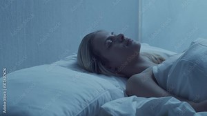 Young woman lying in the bed at night. Beautiful blond sleeping girl. Twilight in the bedroom, moonlight from the window. Stock Video