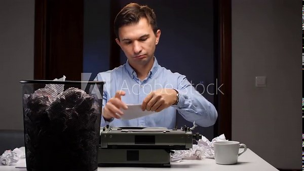 Man experiencing writer's block sitting at a desk with a vintage typewriter, crumpling and discarding multiple sheets of unsuccessful drafts into a overflowing waste bin