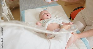 Doctor Performing Abdominal Ultrasound on Newborn Baby in Clinic. A pediatrician conducts an ultrasound on a baby in a medical clinic, using modern ultrasound equipment for accurate diagnostics