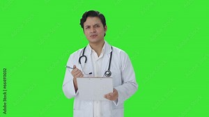 Confused Indian doctor writing patient brief Green screen