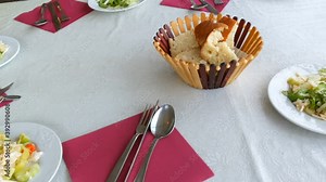 Table setting in the restaurant. Bread in a basket, vegetable salad in a plate, cutlery knife, fork, spoon on a red napkin top view.