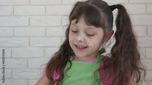 The child is cooking with flour. Happy little girl plays with flour, sprinkles it on the table.