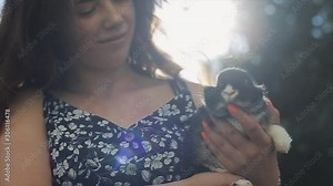 Pretty young girl standing in the sun with a little rabbit in her hand. Close portrait view. The wind blowing girls hair