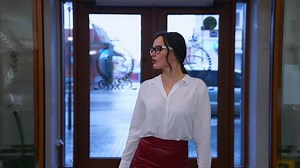 Confident young woman in a luxury hotel. Stylish girl coming into a hotel and moving to the reception desk. Charming lady in glasses indoors.