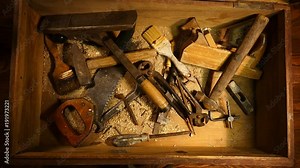 Old hand tool in a wooden chest. Retro tool. Rusty pliers, hammer, file, saw. Old wooden tool box..
