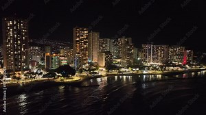 waikiki drone aerial footage at night with bright buildings and lots of light with traffic and palm trees oahu hawaii